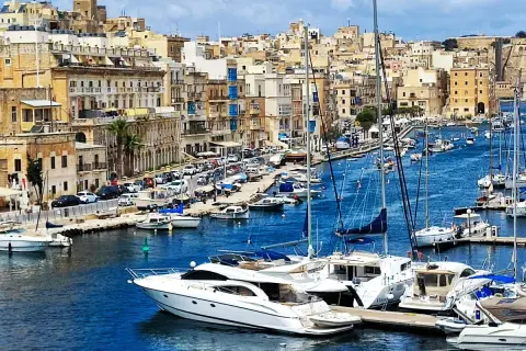 Malta czy warto? Widok na zatokę pełną jachtów i łodzi, z malowniczymi, zabytkowymi budynkami w tle.