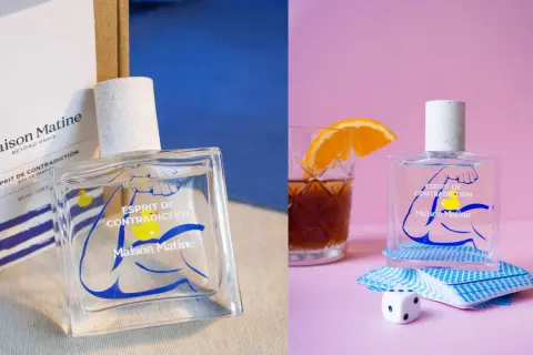 Perfumy Maison Matine Esprit de Contradiction w szklanej butelce z niebieskim wzorem. Obok kostka do gry i talia kart.