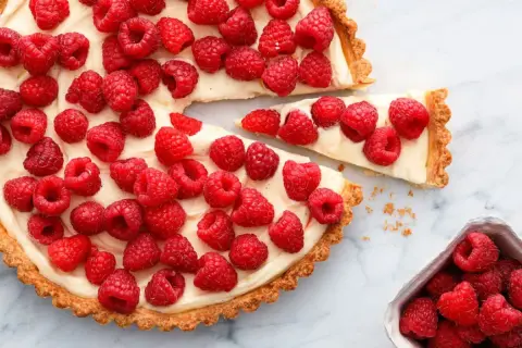 Tarta z malinami i mascarpone, ozdobiona białą czekoladą, kusi świeżością i kremowym nadzieniem.