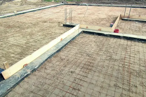 Fundament pod budowę domu, zbrojenie gotowe do zalania betonem. Widać drewniane szalunki i rury. Czekamy na chudziak.
