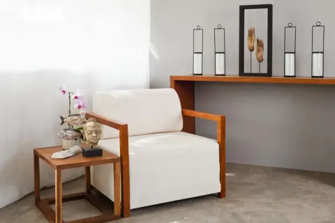Kreative Ideen für eine tote Ecke im Wohnzimmer: Sessel, Beistelltisch mit Buddha-Kopf und Orchidee, Konsolentisch mit Kerzenhaltern und Händen-Deko.