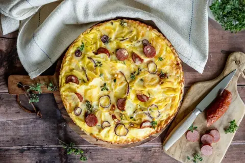 Herzhafte Kartoffeltorte mit Speck und Zwiebeln, goldbraun gebacken und mit frischen Kräutern garniert. Ein Genuss für jeden Anlass.
