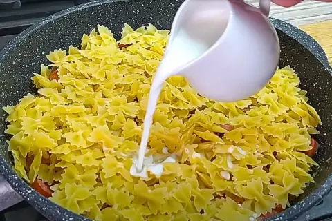 Makaron farfalle z kiełbasą w sosie śmietanowym, gotowany na patelni.