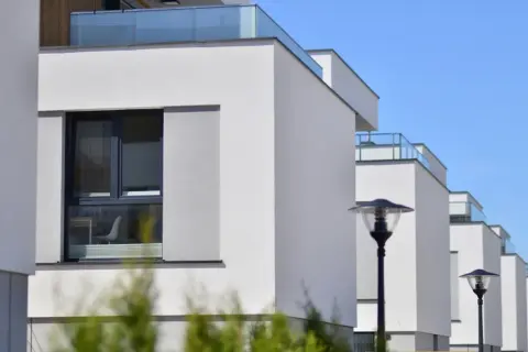 Edificios modernos con fachadas blancas y balcones de cristal, cumpliendo la normativa sobre estética fachadas de edificios.