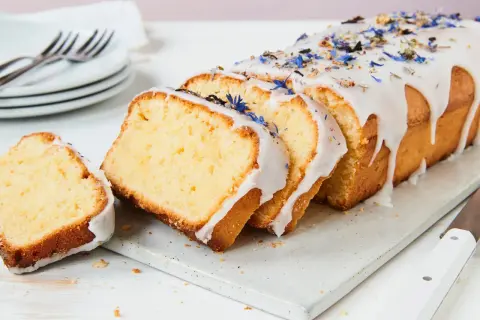 Saftiger Kuchen mit Mascarpone, verziert mit blauen Blüten und Zuckerguss.