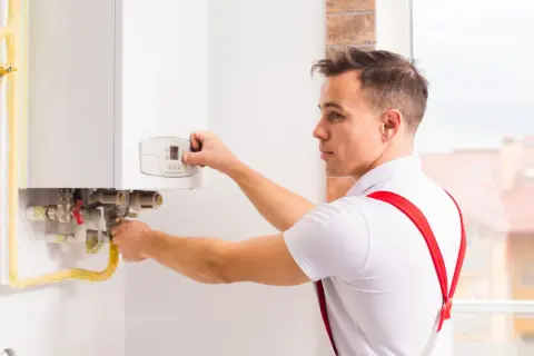 Tecnico esegue verifica caldaia, controllando i collegamenti e il pannello di controllo.