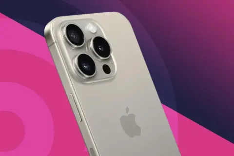 Close-up of a silver iPhone's rear camera array with three lenses and a flash, against a pink and purple gradient background.