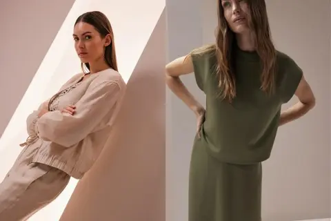 Zwei Frauen in stilvollen, **monochromen Outfits**: eine in Beige mit Leinenjacke und Hose, die andere in Khaki mit Oberteil und Rock.
