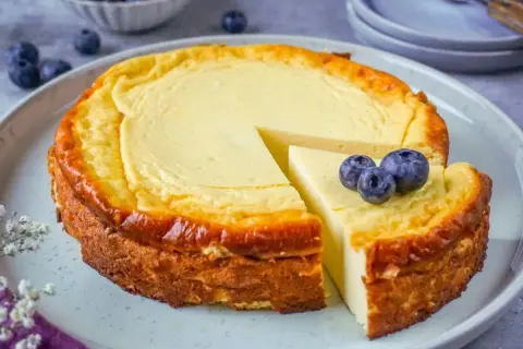 Ein saftiger Quarkkuchen ohne Boden, goldbraun gebacken und mit frischen Blaubeeren garniert. Ein Genuss für jeden Kaffeetisch!