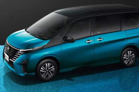 Nowy Nissan Serena w turkusowym kolorze, z czarnym dachem, prezentuje się elegancko na błyszczącym, niebieskim tle.