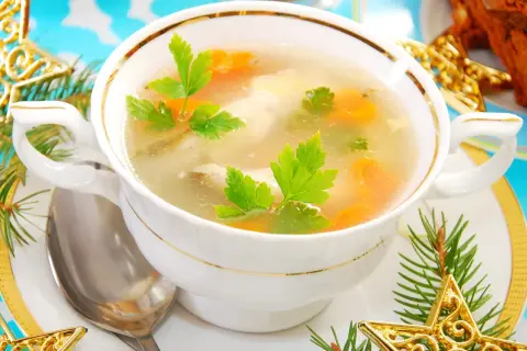 Aromatyczna zupa rybna przepis prosty, podana w eleganckiej miseczce, ozdobiona gałązkami choinki i złotymi gwiazdkami.