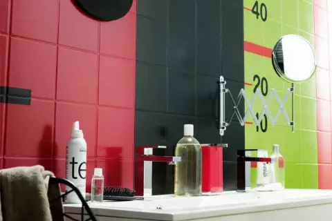 Un mur de salle de bain aux carreaux rouges, noirs et verts, avec des marques de croissance. Une inspiration peinture céramique pour un décor audacieux.
