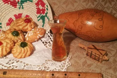 Biscotti decorati, un bicchierino di vernaccia di Oristano, una zucca intagliata e un flauto in legno.
