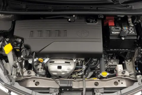 Silnik Toyoty Yaris, widok z góry. Czarna osłona z logo Toyoty, akumulator Varta, płyny i przewody.