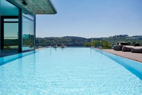 Traumpool mit Blick ins Grüne – perfekter Urlaub in NRW. Zwei Personen genießen das Wasser, während sich im Hintergrund sanfte Hügel erstrecken.