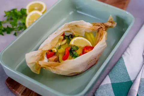 Salmone al cartoccio con patate, pomodorini e limone, pronto per essere infornato.
