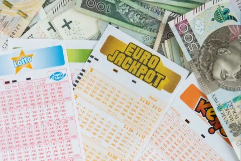 Kupony Lotto i Eurojackpot leżą na stosie banknotów. Zastanawiasz się, ile jest do wygrania w Eurojackpot dzisiaj?