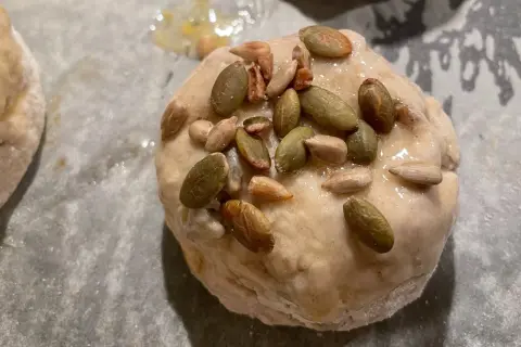 Nybakade glutenfria frallor med pumpa- och solrosfrön på en bakplåt.