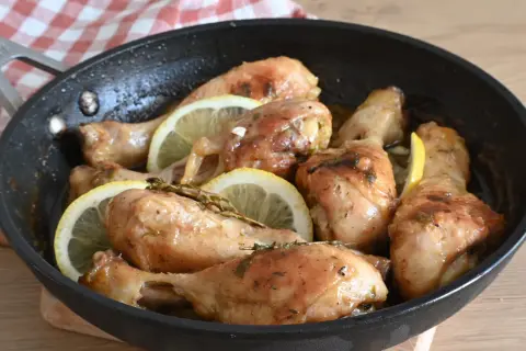Cosce di pollo al limone succulente e dorate, cotte in padella con fette di limone e erbe aromatiche.