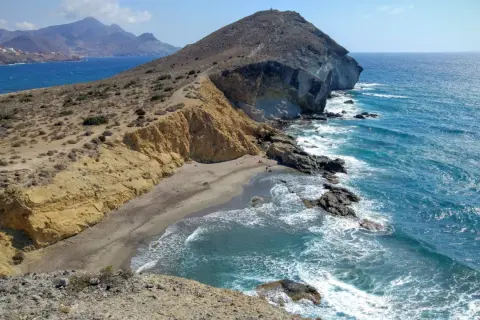 Paisaje de la cala amarilla en Almería, con acantilados dorados, arena y mar azul turquesa.