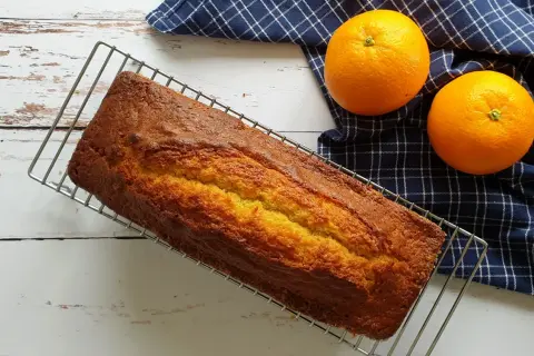 Gâteau doré sur grille, prêt à être dégusté. Une recette gâteau facile et originale, avec des oranges fraîches à côté.