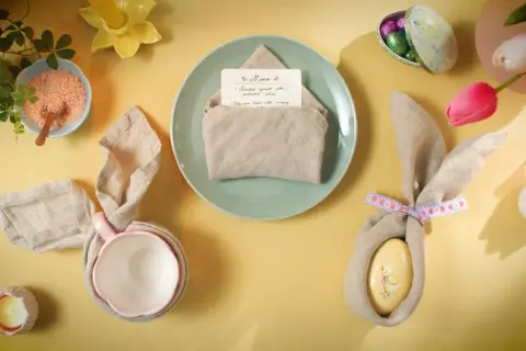Jolie table de Pâques avec un pliage serviette bapteme en forme de lapin, des œufs décorés et des tulipes.