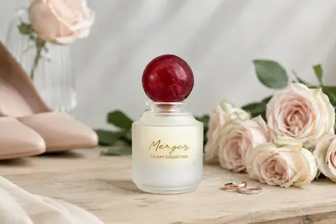 Perfumy na ślub z kolekcji Galaxy, obok różowych róż, eleganckich szpilek i obrączek.