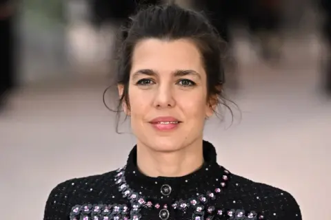 Charlotte Casiraghi, con un'acconciatura raccolta e un abito scuro scintillante, sorride con un'espressione serena.