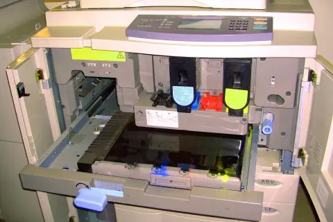 Wnętrze drukarki z widocznymi tonerami i mechanizmem.