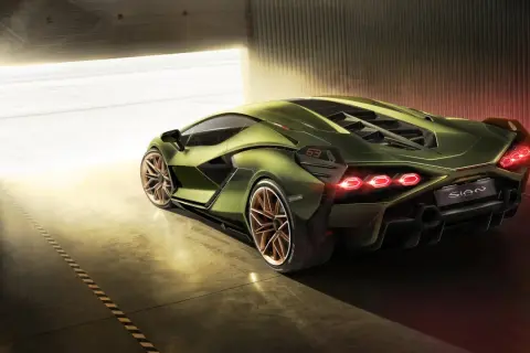 Zielony Lamborghini Sian z miedzianymi felgami, wychodzący z garażu w blasku słońca.