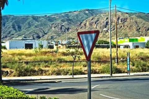 Señal de ceder el paso en una carretera con montañas al fondo.