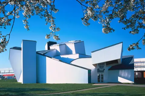 Das Vitra Museum Weil am Rhein, ein architektonisches Meisterwerk, erstrahlt im Frühlingslicht unter blühenden Kirschbäumen.