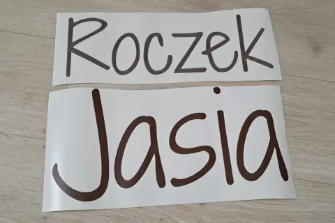 Napis "Roczek Jasia" na białych arkuszach, gotowy do dekoracji przyjęcia.