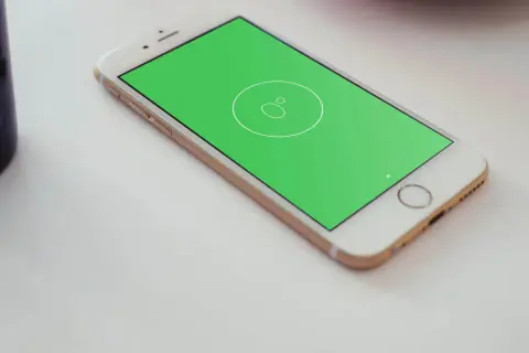 Złoty telefon z zielonym ekranem, na którym widnieje ikona poziomicy. Obok stoi niebieska szklanka.