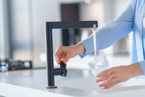 Une personne remplit un verre d'eau du robinet, peut-être pour tester la dureté de l'eau.