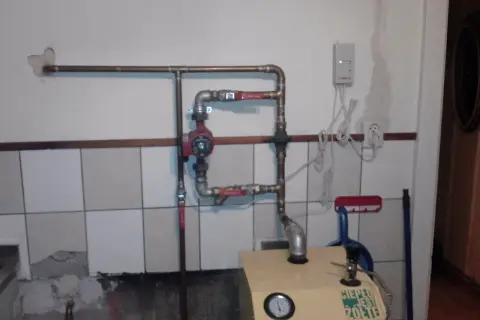 Montaż pompy CO w układzie otwartym. Widoczna instalacja hydrauliczna, czerwona pompa, zawory i fragment kotła.