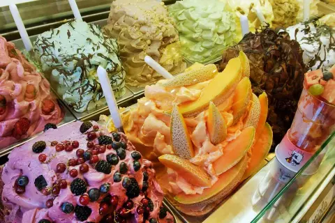 En display med olika sorters italiensk glass, inklusive bär, melon och choklad.