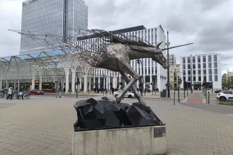 Metalowy jednorożec na skalnej podstawie, symbolizujący dynamikę i nowoczesność, na tle architektury Piotrkowska Łódź.