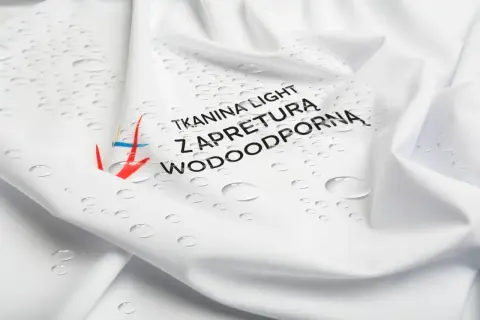 Biała tkanina z kropelkami wody i napisem "Tkanina light z apreturą wodoodporną". Idealna na deszczowe dni.