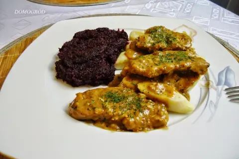 Pyszne polędwiczki w sosie podane z kluskami i buraczkami. Danie wygląda apetycznie i zachęca do spróbowania.