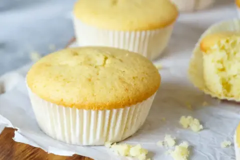 Zarte Muffins, perfekt für das Muffins Grundrezept. Einer ist angeschnitten und zeigt die fluffige Textur.