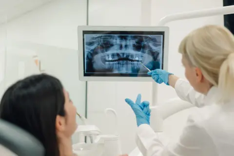 La dentista mostra una radiografia panoramica a una paziente. La visita opt dentista è in corso.