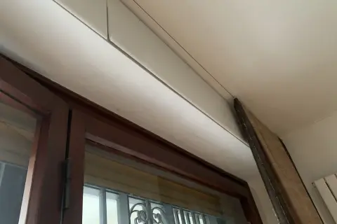 Dettaglio di un cassonetto tapparelle in fase di rimozione, con pannello in legno appoggiato.