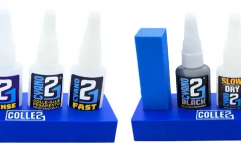 Deux présentoirs bleus avec des bouteilles de super glu CYANO 2 : DENSE, FAST, BLACK, SLOW DRY. Idéal pour les collages professionnels.