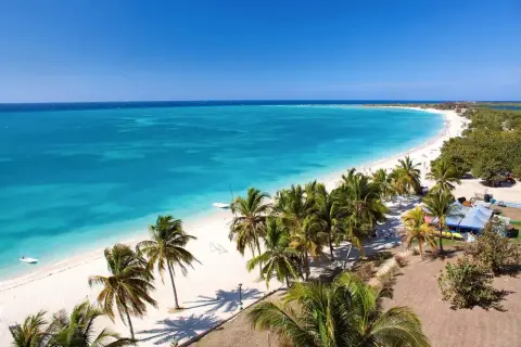 Playa caribeña con palmeras y aguas turquesas, un paraíso antes de la época de huracanes en Cuba.