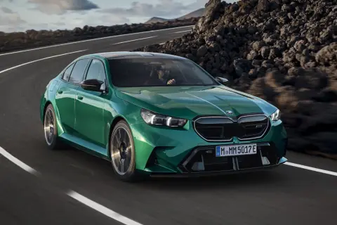 Zielone m5 bmw pędzi po krętej drodze wśród skalistych krajobrazów.