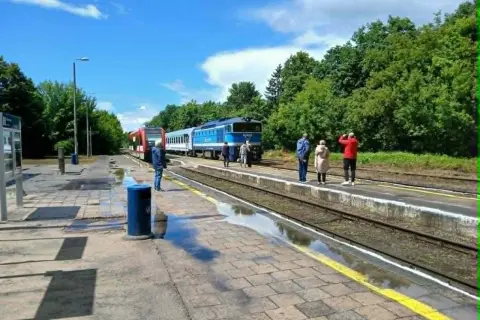 Na peronie czeka pociąg TLK Flisak. Ludzie sprawdzają rozkład jazdy, gotowi do podróży.