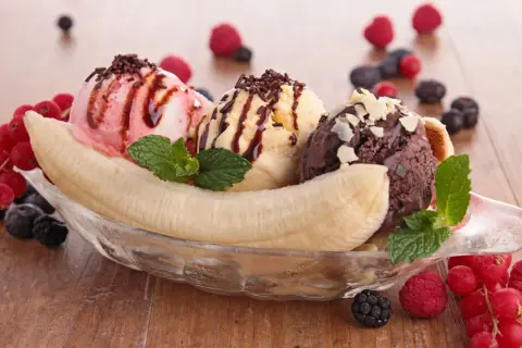 Ein klassisches Banana Split Eis mit drei Kugeln Eis, Banane, Beeren und Schokoladensauce.