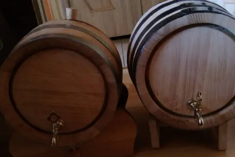 Dwa drewniane beczki, jedna z korkiem, druga z kranikiem, czekają aż coś w nich dojrzewa w dębowych beczkach.