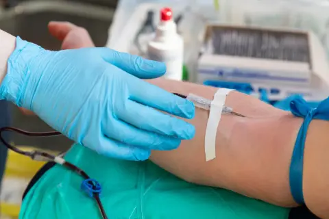 Ręka w błękitnej rękawiczce medycznej pobiera krew. To ważny moment, bo każda kropla, niezależnie od grupy krwi, ratuje życie.